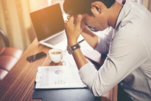 Stressed professional hunched over a report on his desk