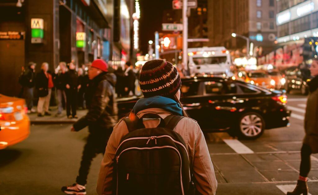 Woman in beanie looking sideways before crossing the street in the evening