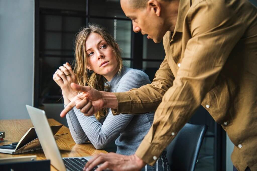 A woman being harassed by a man in a workplace environment