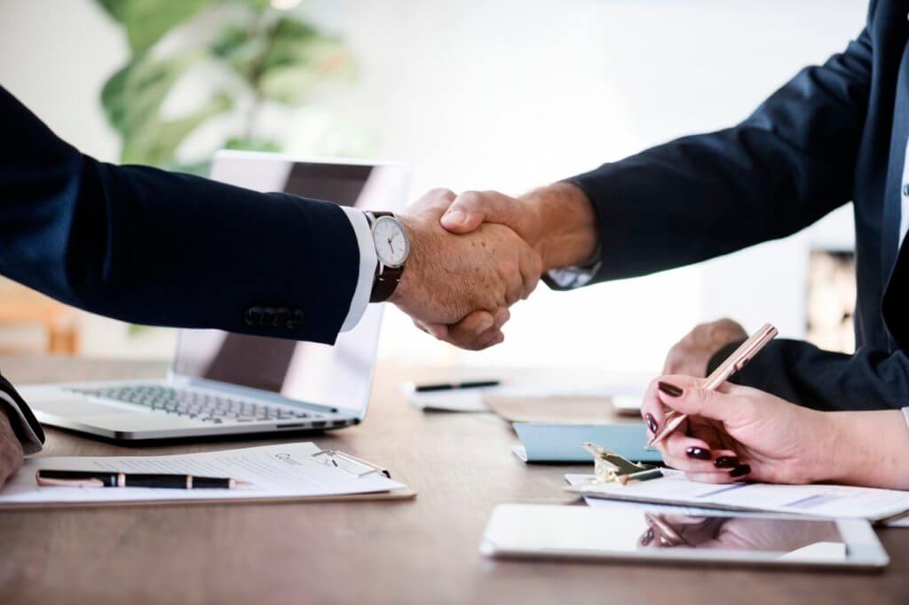Two men in suits shaking hands during an insurance negotiation process