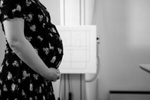 Black and white photograph of a pregnant woman in a floral dress