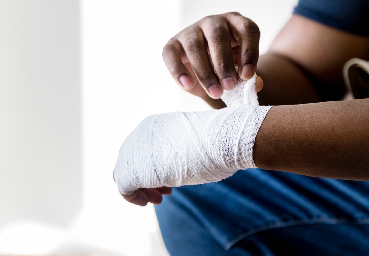 man wearing jeans wrapping white bandage around hand and wrist due to a workplace injury