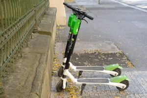 two Lime electric scooters parked on the sidewalk
