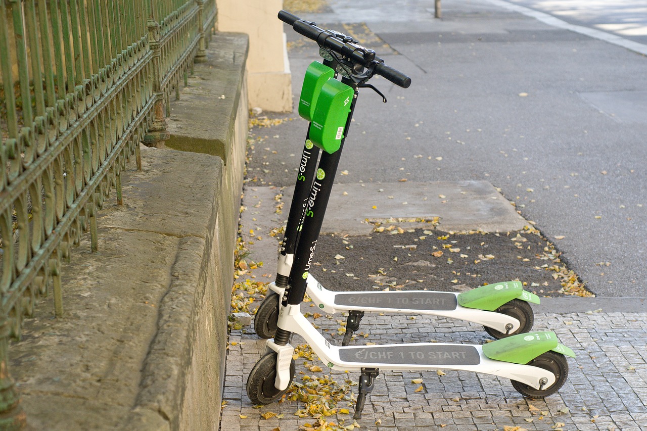 two Lime electric scooters parked on the sidewalk