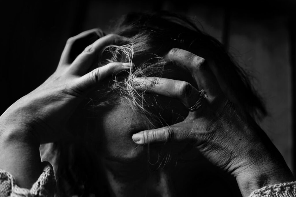 Black and white image of crying woman in distress grabbing her hair