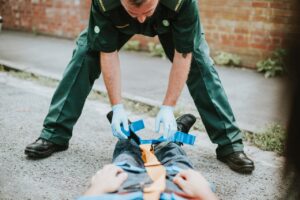 Paramedic wearing blue gloves securing man’s feet on stretcher