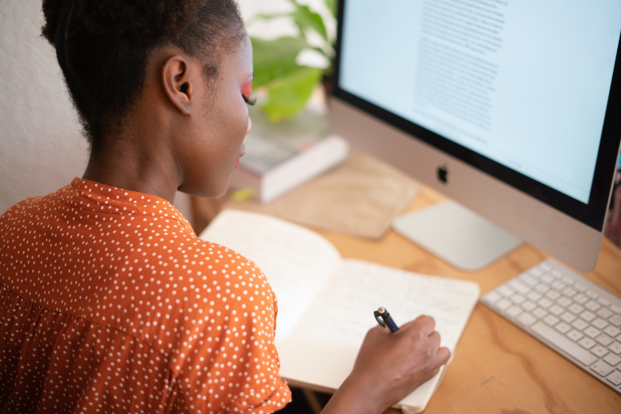 woman writing on her notebook at her workstation