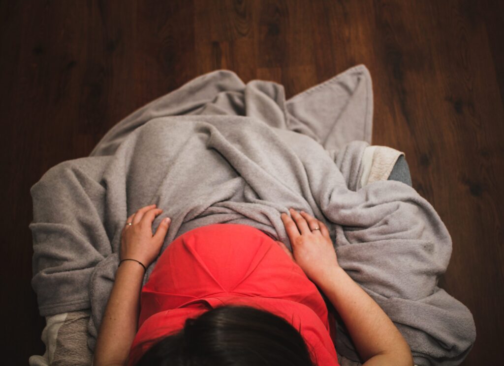 Pregnant woman covered in a gray blanket